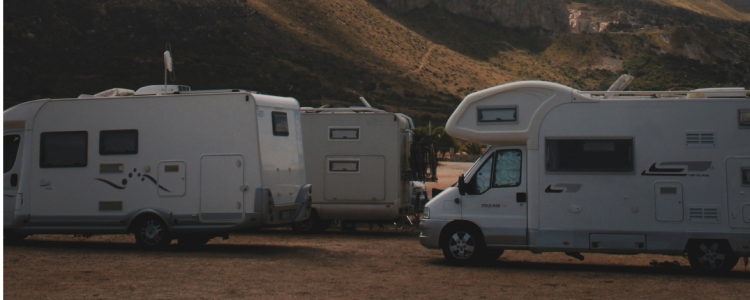 Hulpluchtvering voor campers – stabiel staan op elke bestemming Meerdere campers geparkeerd op een camping in een bergachtig landschap bij schemerlicht